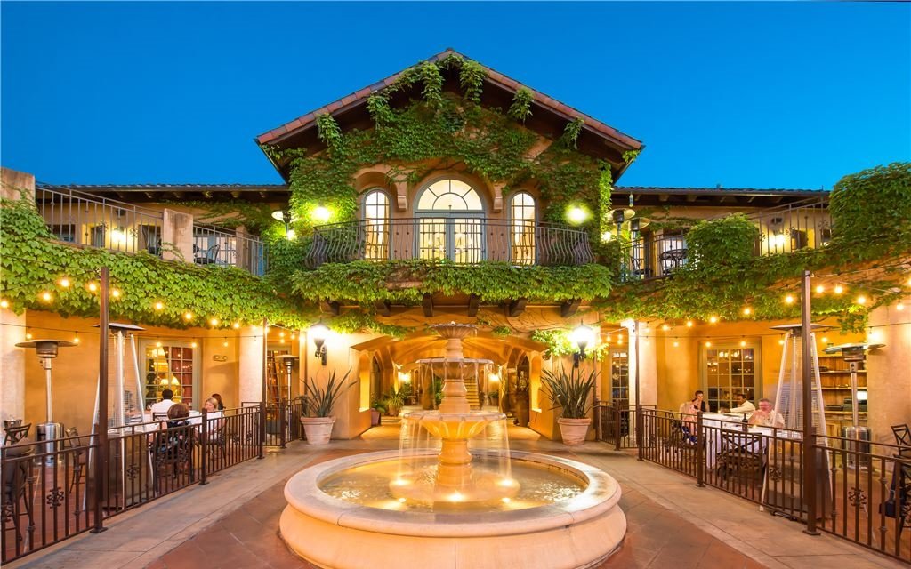 Warmly lit outdoor eating space with fountain and vine-covered walls